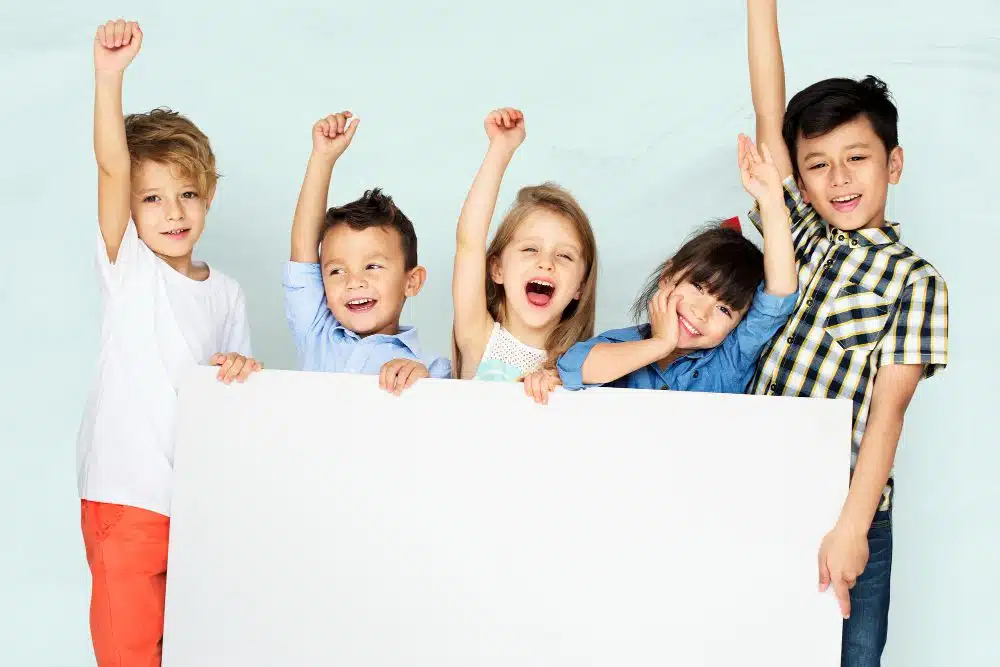 little kids cheering while holding white board 1